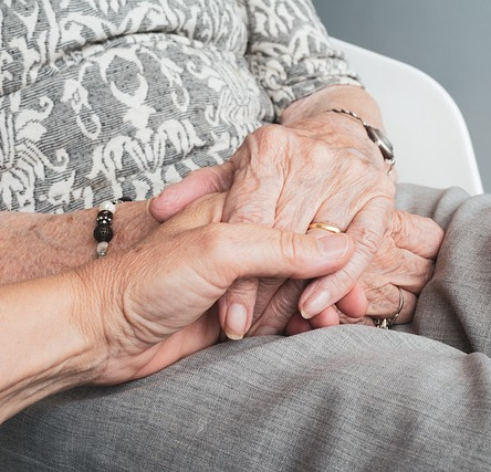 Hands of an older woman holding another hand